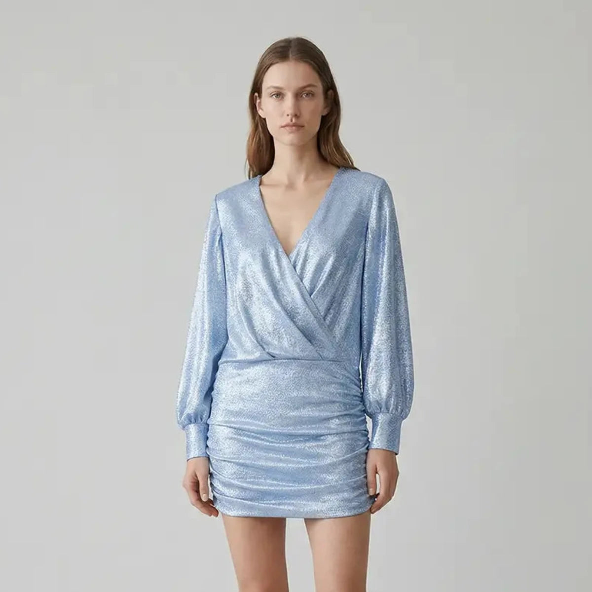 Abito corto drappeggiato in lurex azzurro MIA con scollo a V incrociato e maniche lunghe indossato da modella – Alessandra Gallo
