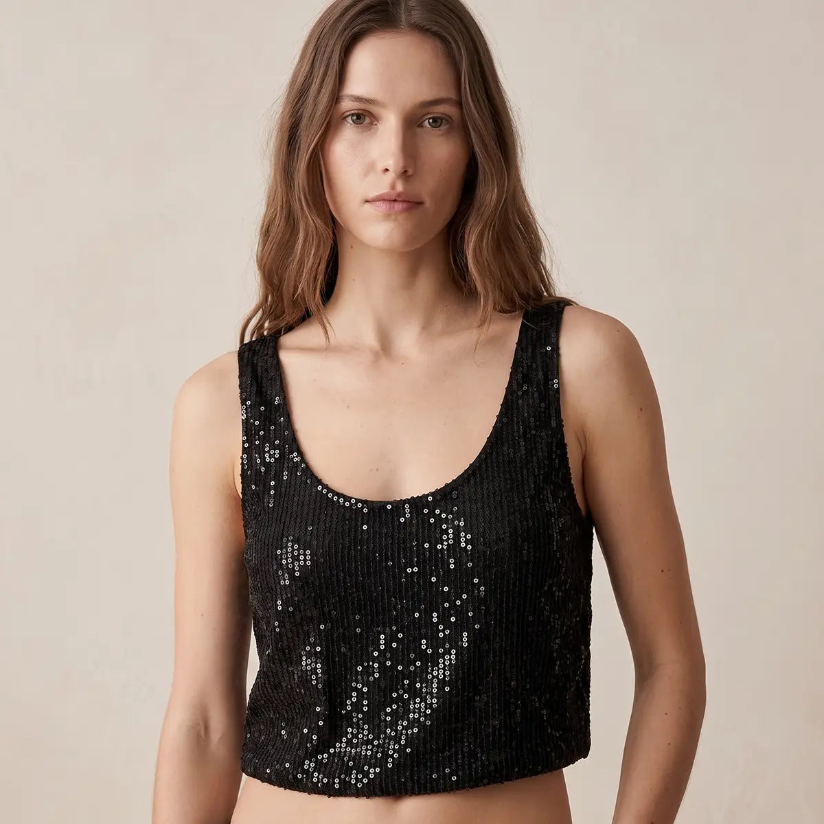 ANDROMEDA, crop top in paillettes nere con scollo rotondo e spalle larghe, su modella.