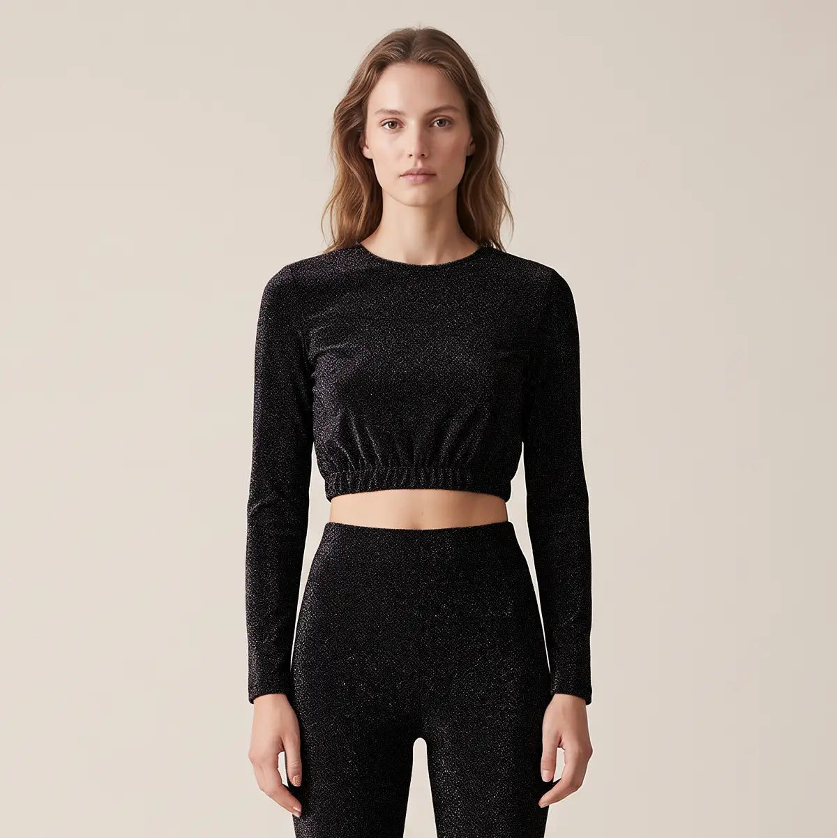 BICE, crop top in lurex nero con girocollo e maniche lunghe, su modella.