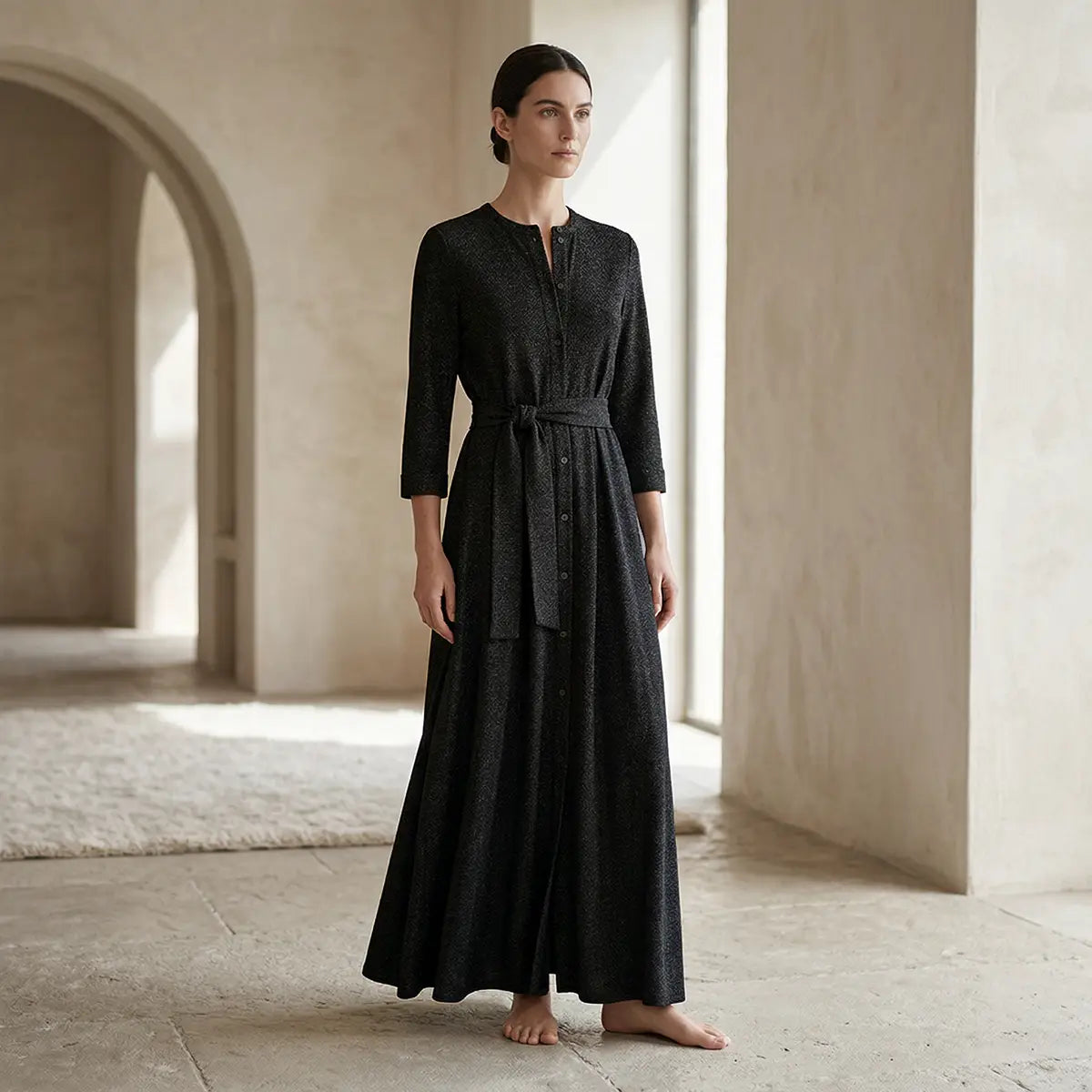 CLELIA, abito lungo in lurex nero con cintura, bottoni sul davanti e gonna ampia, su modella.